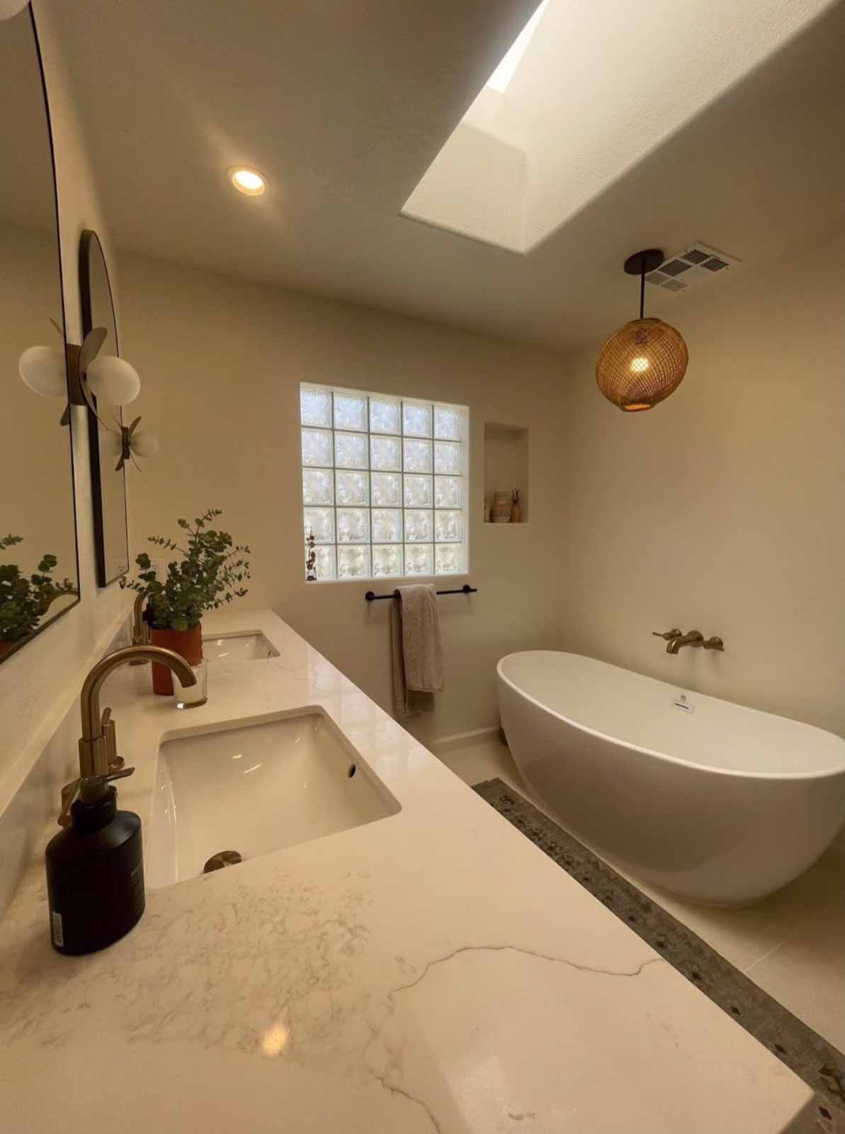 Glendale master bathroom with freestanding white soaking tub, skylight, and glass block window