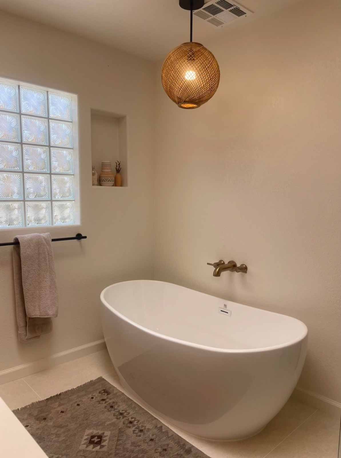 Freestanding soaking tub with rattan pendant light and brass wall faucet - Glendale spa bathroom