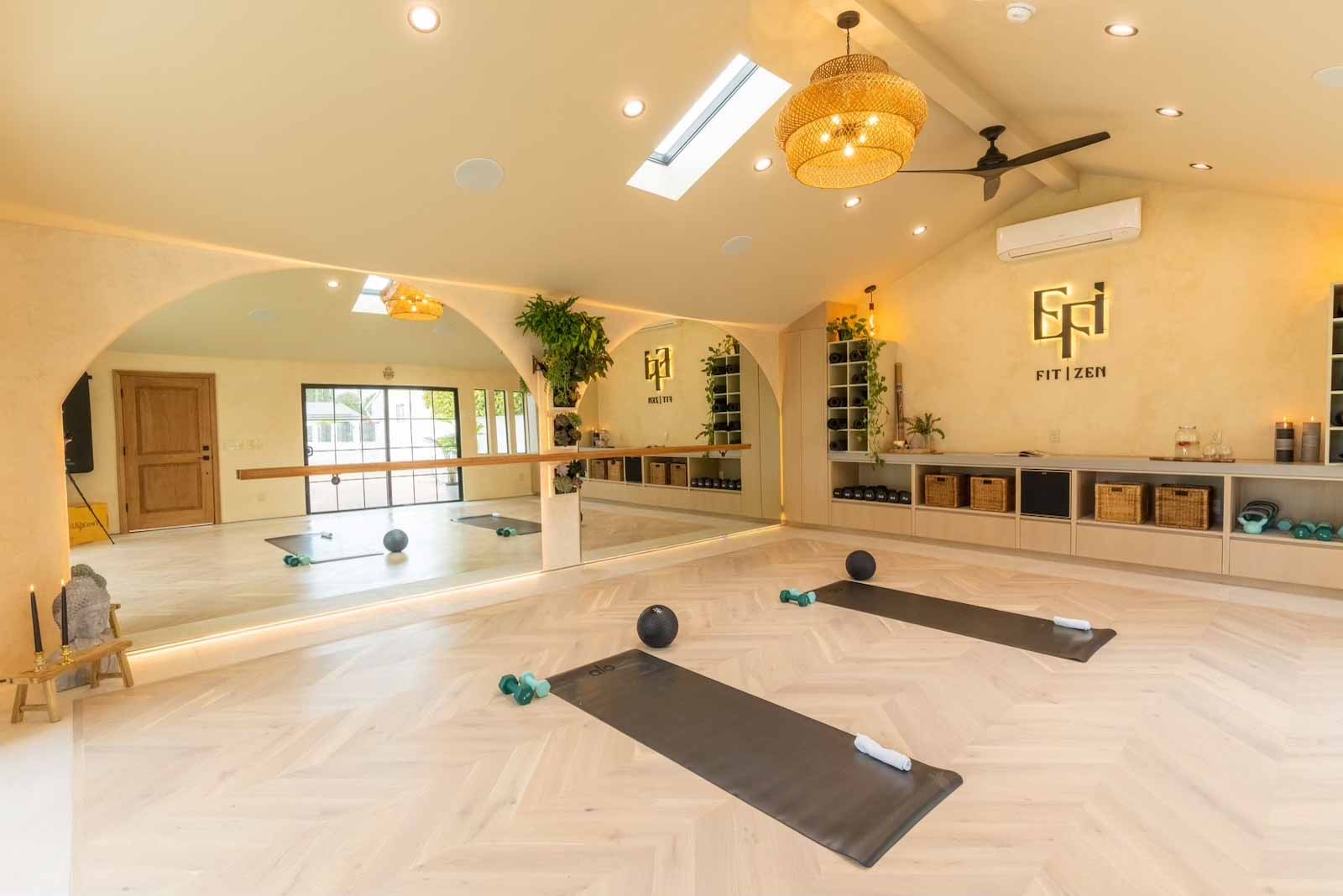 Wide view of yoga studio with vaulted ceiling, storage, barre, and equipment