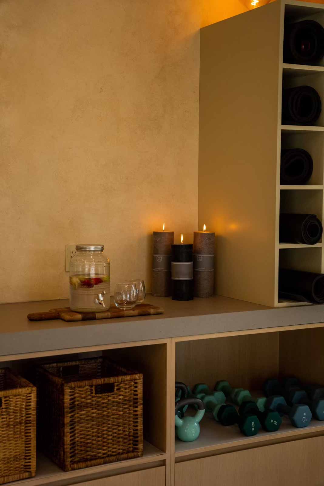 Built-in storage with yoga mat cubbies, baskets, candles, and weights