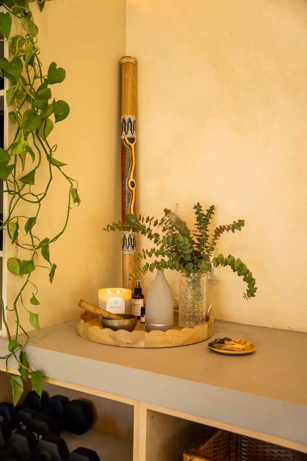 Zen corner with candle, singing bowl, eucalyptus vase, and didgeridoo