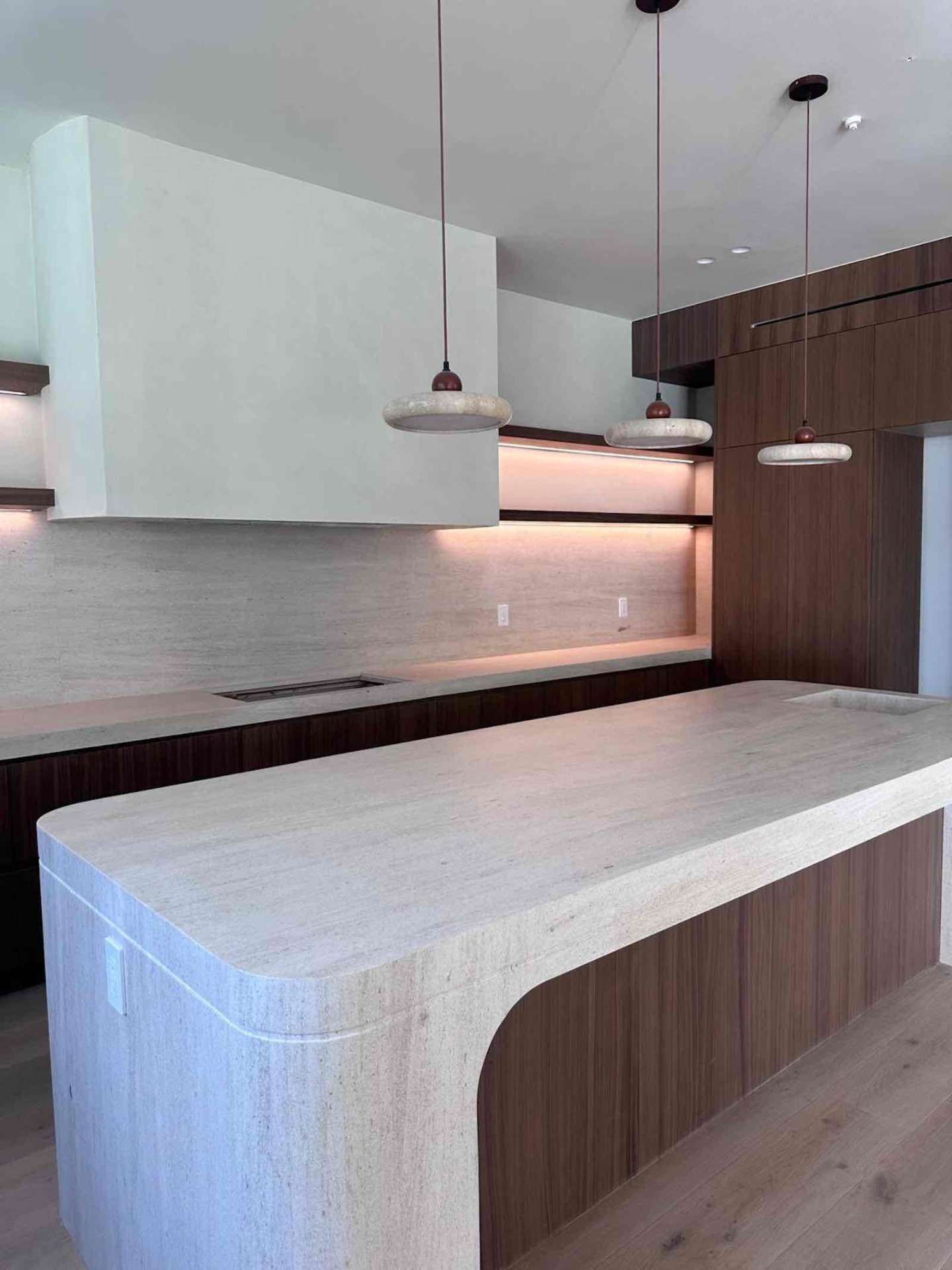 Encino ADU kitchen detail with stone pendants, travertine countertops, and LED under-cabinet lighting
