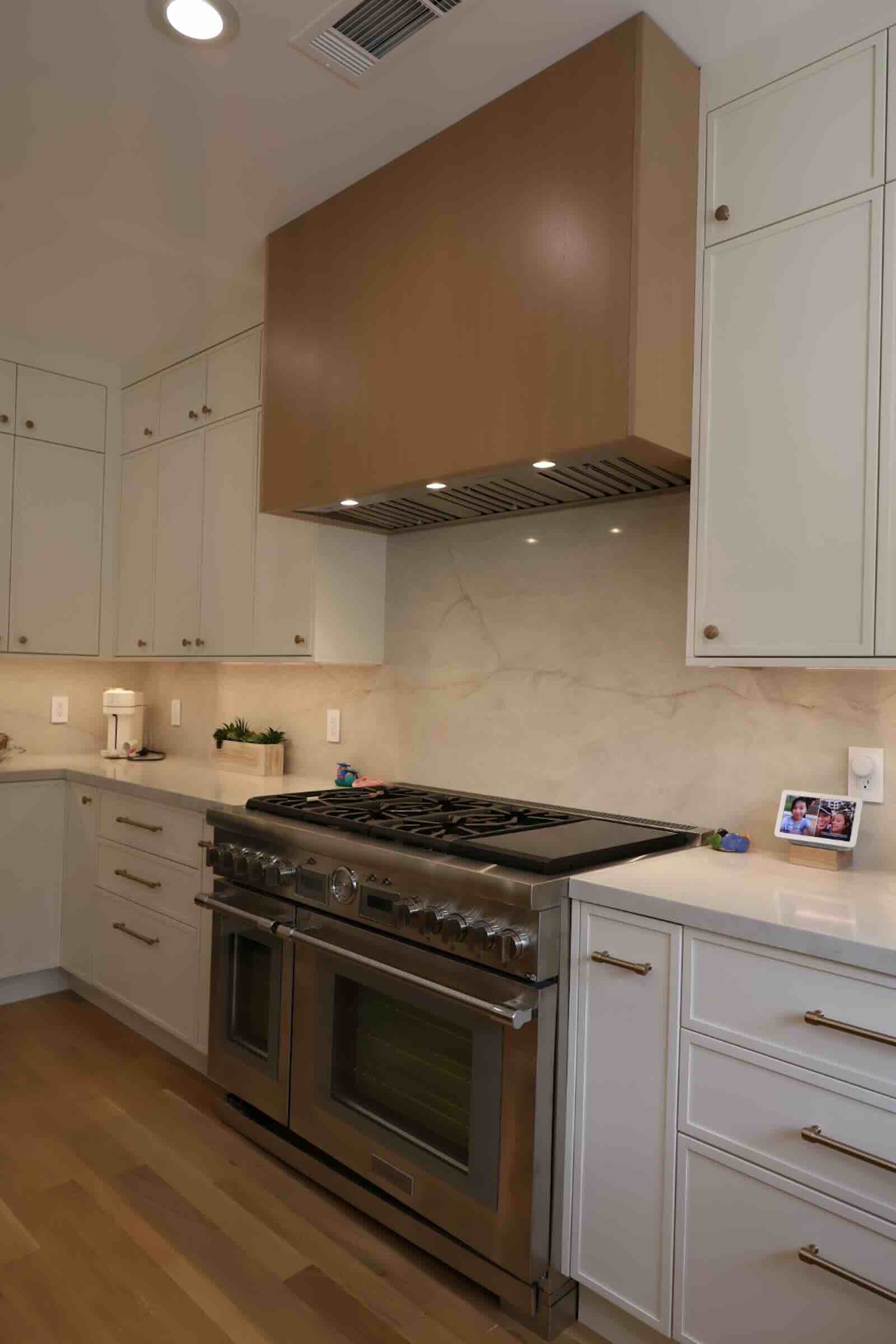 La Cañada Flintridge kitchen stainless range with wood-tone hood and stone backsplash